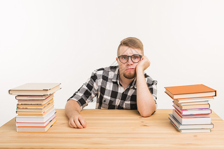 人 知识和教育理念  疲惫的男学生坐在桌边 书堆成山 不想学习教科书快乐成人衬衫考试头发格子眼镜工作男性背景图片