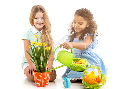两个小女孩在地板上浇鲜花和玩弄花朵高清图片