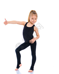 体操选手的小姑娘露出拇指健身房活力微笑女性快乐乐趣孩子女孩工作室幸福背景