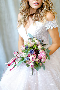 年轻新娘在摄影工作室穿着白礼服和花束背景图片