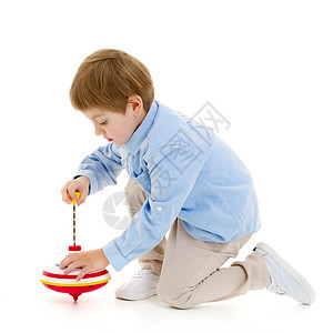 小男孩在玩花招游戏玩具陀螺蓝色操场地面童年男性儿子快乐木马背景图片