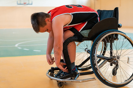 男孩坐在轮椅上 为大竞技场的篮球赛开始做准备 准备比赛乐趣竞赛运动疼痛娱乐椅子保健残障篮球人士背景图片