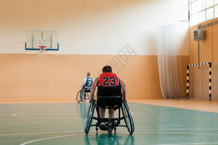 男孩坐在轮椅上 为大竞技场的篮球赛开始做准备 准备比赛机动性训练动机娱乐男生竞赛一体化运动员残障运动背景图片