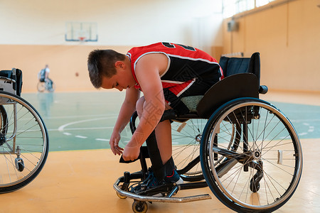 男孩坐在轮椅上 为大竞技场的篮球赛开始做准备 准备比赛运动员保健男生车轮人士残障卫生运动椅子乐趣背景图片
