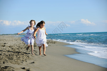 沙滩跑可爱的小女孩在沙滩上奔跑假期孩子们女性跑步朋友们季节海滩海洋衣服家庭背景