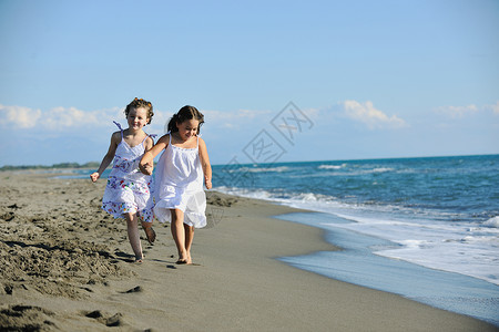 沙滩跑可爱的小女孩在沙滩上奔跑喜悦姐姐假期旅行海洋衣服乐趣季节朋友们海岸背景