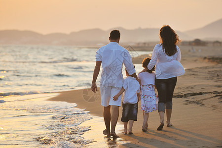 我们得海洋快乐的年轻家庭 在日落时在海滩上玩得开心母亲成人男性跑步喜悦父亲旅行孩子妈妈男生背景