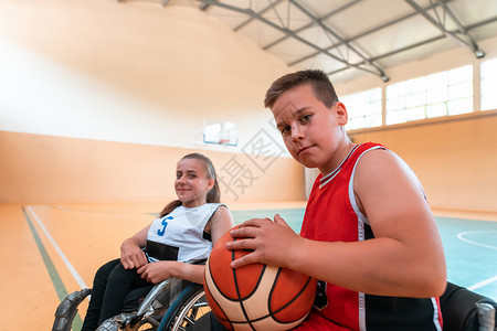 男孩坐在轮椅上 准备在大竞技场的篮球赛开始 有选择地集中关注篮子男生法庭康复乐趣残障椅子竞赛运动疾病背景图片