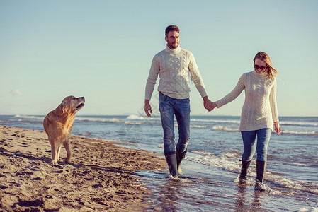 狗手在自闭症日海滩上玩得开心的狗情侣男性男朋友享受丈夫夫妻海岸女士海洋男人妻子背景