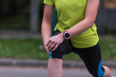女跑者在上午训练前升温和伸展有氧运动女孩森林运动员公园城市跑步女性女士慢跑者背景