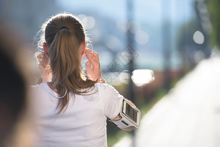 女孩手机查路线慢跑前先打个电话臂章音乐播放器手臂蓝色女士女孩慢跑者音乐训练太阳背景