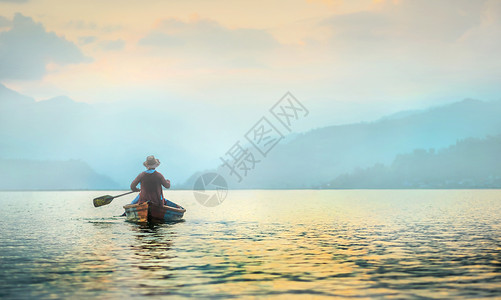 清晨湖上的孤单渔民男人文化帽子日出村民男性天空独木舟风景渔夫背景图片