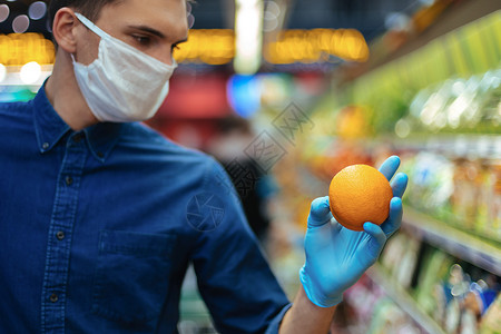 在超市挑选橘子的时候 戴着保护面具的人会很紧张的产品健康感染男人危险部门手套食物流感货架背景图片