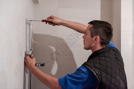 在卫生间工作的专业水管工安装房子男性维修建筑淋浴服务扳手修理工龙头工具高清图片素材