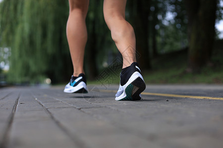 运动鞋底跑步者脚踏在路上 紧贴鞋底 日落或日出时户外赛跑者女性成人训练女士娱乐慢跑者速度闲暇活动背景