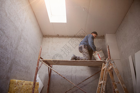 建筑工人用石膏封印在石膏上限上天花板工具泥水匠装修工作男性房子石膏板建设者房间背景图片