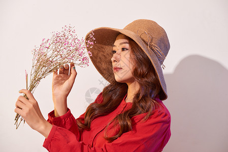 一位穿着夏衣和草帽的可爱年轻女士 在拿着花朵时装扮花束魅力帽子时尚微笑快乐成人女孩红色女性背景图片