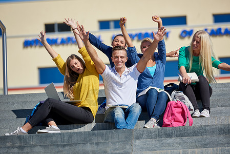 校外学生坐在台阶上大学团队男性背包微笑学校楼梯电脑生活教育背景