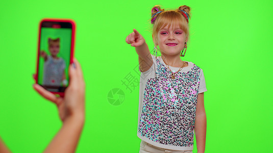 绿屏素材跳舞有趣的小少女小孩在相机拍摄录像时跳舞 在染色墙上用电话拍到手机摄影机博主爱好音乐社交广告屏幕记录溪流班级背景