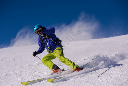 滑雪者在下坡时玩得开心滑雪速度行动衣服空气晴天山腰娱乐男人竞赛背景图片