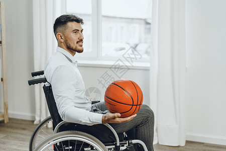 手持篮球轮椅的残疾青年男子运动员残障车轮动机椅子人士竞赛玩家运动背景图片