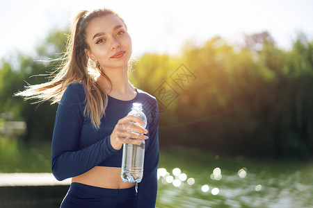 在公园穿蓝色运动衣饮用水的年轻美容女子肖像 照片来自女士运动员青少年女性成人口渴青年脱水女孩黑发背景图片