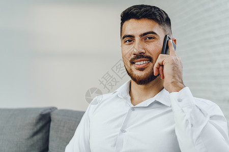 成功的青年商务人士在用手机交谈时使用自己的手机商务讨论办公室管理人员企业家讲话建筑电话说话男性背景图片