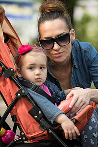母亲婴儿车公园中的母亲和婴儿婴儿车快乐父母太阳镜儿子男生家庭孩子运输童年背景