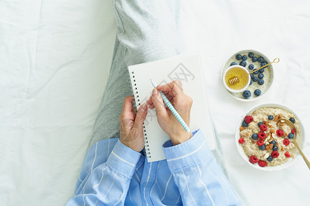 女人用大白白开放的笔记本写作 躺在床上高清图片