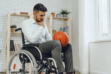 手持篮球轮椅的残疾青年男子车轮玩家椅子运动动机竞赛人士运动员残障背景图片