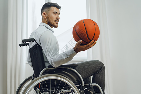 手持篮球轮椅的残疾青年男子残障人士玩家竞赛运动员椅子动机运动车轮背景图片
