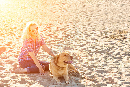身着太阳镜的年轻美人肖像 坐在沙滩上 带着金色猎犬 海路女孩与狗同行乐趣动物感情运动女孩女性海洋友谊游戏朋友背景