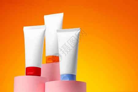 橙色背景的白白化妆品空容器凝胶皮肤管子瓶子护理润肤产品包装洗剂卫生背景图片