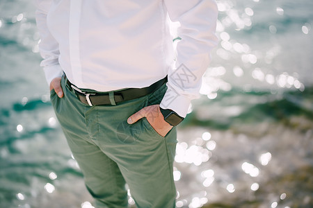 穿绿裤子的人用手放在口袋里 压过闪亮的水面背景图片