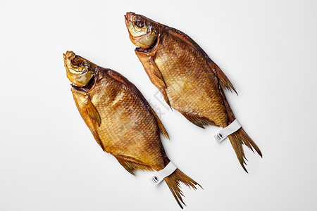 两支烟熏血清 上面贴有标签 在白色背景的尾巴上隔绝食物小样治愈盐渍美味海鲜淡水啤酒鲤鱼营养背景图片
