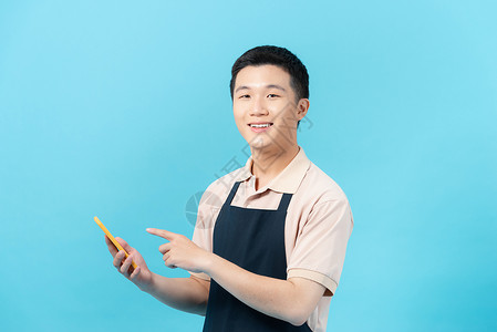 带智能手机的亚洲人电话男性手势厨师围裙短信工具烹饪服务男人背景图片