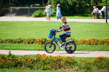 快乐的男孩 学会骑他的第一辆自行车运动头盔活动骑术安全男生童年闲暇乐趣公园背景图片