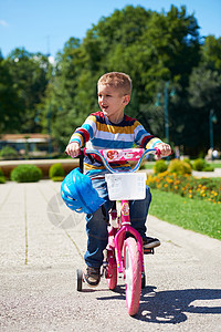 快乐的男孩 学会骑他的第一辆自行车骑术闲暇男性童年公园活动运动头盔孩子安全背景图片