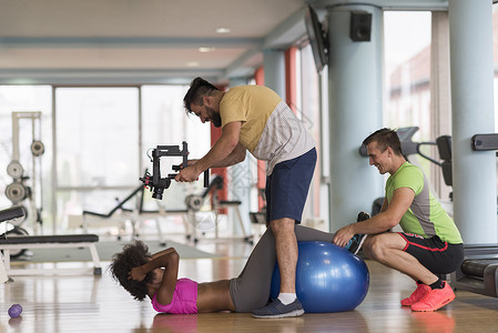 在体育馆与个人教练员一起做运动锻炼运动装夫妻培训师帮助药片俱乐部成人训练蓝色背景图片