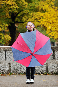 带雨伞的快乐女孩幸福喜悦衣服树叶童年生活公园天气女性季节背景图片
