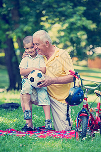 玩足球老人爷爷和孩子在公园玩得开心幸福微笑孙子自行车祖父童年乐趣男人闲暇儿子背景