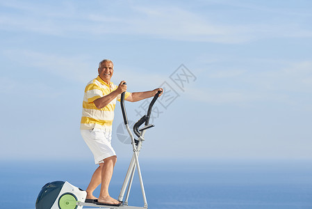 老年健康健健健男子健身天空阳台有氧运动男性机器训练白色老年健身房海洋背景图片
