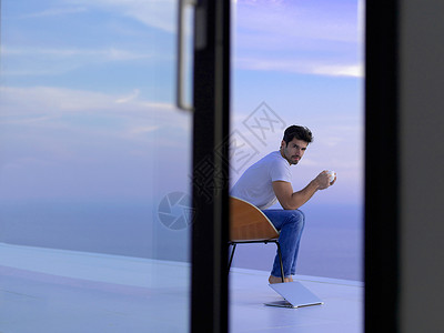 在阳台上在家的放松青年男子电脑咖啡笔记本技术商业男人背景图片