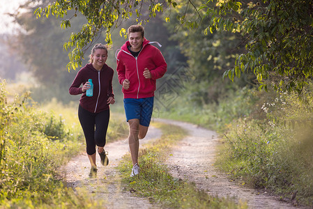 森林慢跑在乡村公路上慢跑的年轻夫妇活力男人运动阳光活动农村森林冒险男性跑步背景