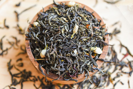 茉香奶茶木碗上的中国干茶 煮红茶的茉奶茶 黑茶叶背景