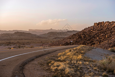 岩石路在日落的犹他州沙漠公路 原始的岩石景观 美国犹他州背景