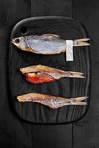 黑木板上含鱼子酱的整体和皮肤咸盐 空气钻过的蟑螂鱼海鲜熏制盐渍小吃鱼子美味营养淡水啤酒服务背景图片