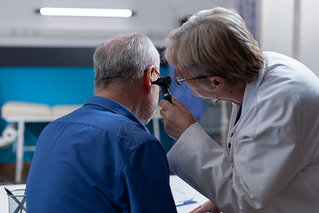 耳炎持有眼镜的医生为病人进行检查探视时做耳腔咨询背景