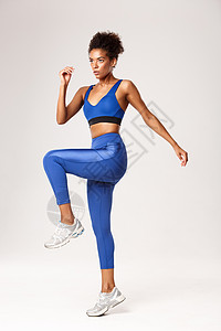 穿着蓝色运动服在健身房锻炼的全长坚定健身女孩 看起来严肃 站在白色背景上背景图片