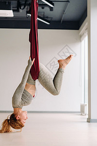 灰色吊床一个女人挂在吊吊吊吊床上 在健身房做瑜伽活动灰色反重姿势重力俱乐部女士吊床训练衣服背景